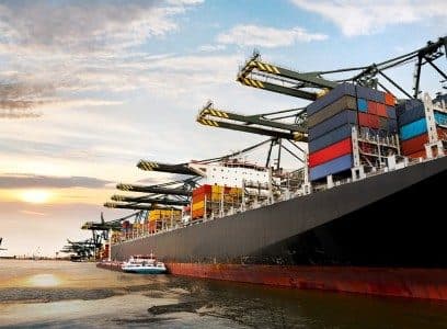 Cranes loading containers onto a ship at sunset