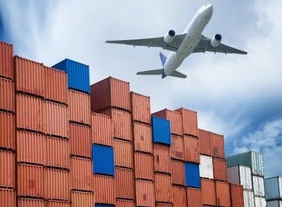 Aircraft flying over stacked shipping containers
