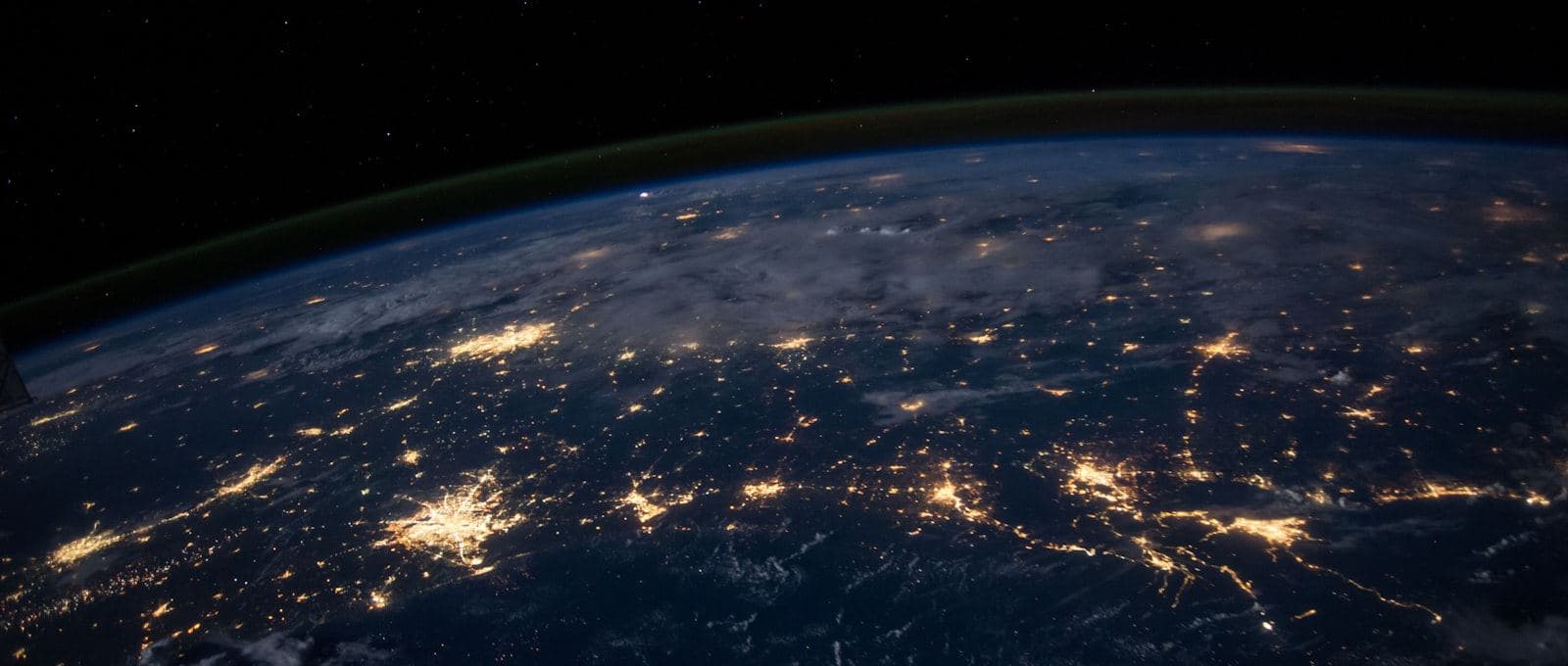 The Earth at night seen from space, city lights tracing global trade routes